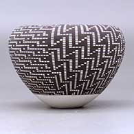A black on white jar with an infinity rim and decorated with a four-panel geometric design built of filling in tiny squares in a grid, click or tap to see a larger version