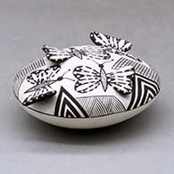 A black on white seed pot decorated with butterfly wing appliques and a butterfly, fineline and geometric design, click or tap to see a larger version