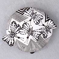 A black on white seed pot decorated with butterfly wing appliques and a butterfly, fineline and geometric design
 by Alisha Sanchez of Acoma