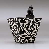 A black on white lidded pyramidal box decorated with a geometric design, click or tap to see a larger version