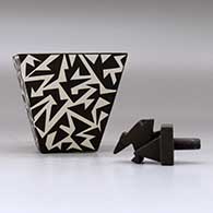 A black on white lidded pyramidal box decorated with a geometric design, click or tap to see a larger version