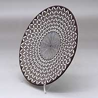 A black on white plate decorated with a yucca leaf snowflake, North Star fineline and geometric design, click or tap to see a larger version