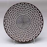 A black on white plate decorated with a yucca leaf snowflake, North Star fineline and geometric design
 by Rebecca Lucario of Acoma