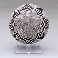 A black on white seed pot decorated with a butterfly wing applique and a butterfly, fineline and geometric design
 by Alisha Sanchez of Acoma