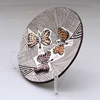 A small polychrome plate decorated with butterfly wing appliques and a butterfly, fineline and geometric design, click or tap to see a larger version