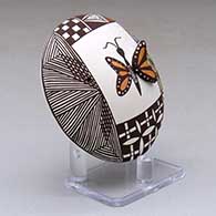 A polychrome seed pot decorated with butterfly wing and lady bug appliques and a butterfly, fineline, checkerboard and geometric design, click or tap to see a larger version