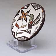 A small polychrome plate decorated with a hummingbird, flower and geometric design, click or tap to see a larger version