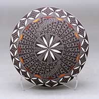 A polychrome seed pot decorated with a fineline, yucca leaf snowflake and geometric design above the shoulder
 by Rebecca Lucario of Acoma