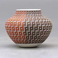 A small jar decorated with a four-panel geometric design built of tiny colored squares, click or tap to see a larger version