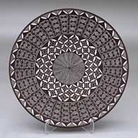 A black on white plate decorated with a North Star fineline, yucca leaf snowflake and geometric design
 by Rebecca Lucario of Acoma