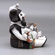 A sitting grandmother storyteller figure holding two children and kittens, butterflies, lady bugs, a bird and a pot, click or tap to see a larger version