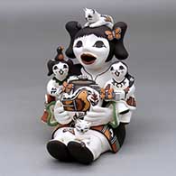 A sitting grandmother storyteller figure holding two children and kittens, butterflies, lady bugs, a bird and a pot
 by Marilyn Ray of Acoma
