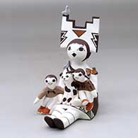 A sitting grandmother storyteller figure wearing a tablito and holding two children with a cat, butterfly and birds
 by Judy Lewis of Acoma