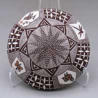 A polychrome seed pot decorated on top with a fineline, quail, hummingbird, dragonfly, butterfly and geometric design with a lady bug applique on the back
 by Carolyn Concho of Acoma