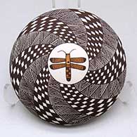 A polychrome seed pot decorated above the shoulder with a dragonfly surrounded by a spiraling fineline and checkerboard geometric design
 by Sharon Lewis of Acoma