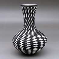 A black on white vase decorated with a spiraling checkerboard geometric design
 by Paula Estevan of Acoma