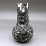 A black on white vase with a tall neck, kiva step cut opening and decorated with a fineline, kiva step and geometric design
 by Paula Estevan of Acoma