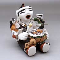 A sitting drumming storyteller figure with two children, a puppy, birds, lady bugs and decorated with a parrot, flower and geometric design
 by Marilyn Ray of Acoma