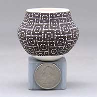 A miniature black on white jar decorated with a  geometric design built of tiny squares
 by Frederica Antonio of Acoma