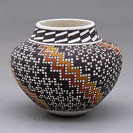 A small polychrome jar decorated with a four-panel spiraling geometric design built of tiny colored squares
 by Frederica Antonio of Acoma