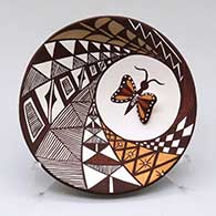 A polychrome plate with appliques and painted with a butterfly, lady bug, fineline and geometric design
 by Carolyn Concho of Acoma