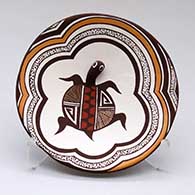 A shallow polychrome bowl with appliques and painted with a turtle, lady bug, fineline and geometric design
 by Carolyn Concho of Acoma