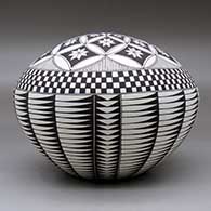A black on white seed pot decorated with a feather, flower, checkerboard and geometric design, click or tap to see a larger version