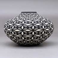A black on white jar decorated with a pumpkin seed snowflake and geometric design, click or tap to see a larger version