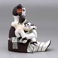 A sitting grandmother storyteller figure with three children, a kitten and a butterfly, click or tap to see a larger version