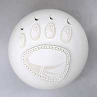 A white seed pot decorated with appliques and sgraffito design of a bear paw and bird, with cutouts for the claws
 by Wilfred Garcia of Acoma