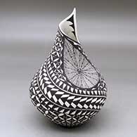 A black on white indented jar with an organic opening and decorated with a pumpkin seed snowflake, kiva step and geometric design
 by Sandra Victorino of Acoma