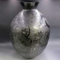 A large glossy black jar with a wide flared rim and sgraffito hummingbird, flower and vine design
 by Arturo Quezada of Mata Ortiz and Casas Grandes