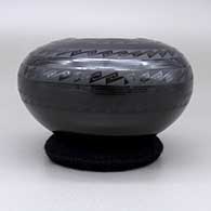 A black on black jar with a square geometric cut opening and a geometric design, click or tap to see a larger version