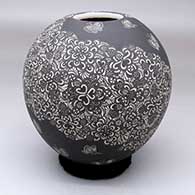A black-on-white jar decorated with a spiral band of sgraffito butterflies among multiple geometric designs
 by Hector Javier Martinez of Mata Ortiz and Casas Grandes
