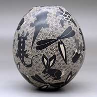 A black-on-white jar decorated with a sgraffito animal, bird, turtle, insect and geometric design, click or tap to see a larger version