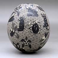 A black-on-white jar decorated with a sgraffito animal, bird, turtle, insect and geometric design, click or tap to see a larger version