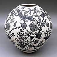 A black-on-white jar decorated with a lightly-carved and sgraffito flying bat, flowers and milk thistle design
 by Adrian Corona of Mata Ortiz and Casas Grandes