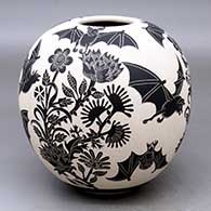 A black-on-white jar decorated with a lightly-carved and sgraffito flying bats, flowers and milk thistle design
 by Adrian Corona of Mata Ortiz and Casas Grandes