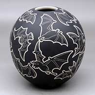 A black-on-white jar decorated with a lightly-carved and sgraffito flying bat design
 by Adrian Corona of Mata Ortiz and Casas Grandes