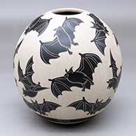 A black-on-white jar decorated with a lightly-carved and sgraffito flying bat and milk thistle design
 by Adrian Corona of Mata Ortiz and Casas Grandes