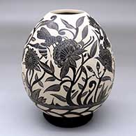 A black-on-white jar decorated with a sgraffito honeybee, flower, leaf and vine design
 by Diana Loya of Mata Ortiz and Casas Grandes