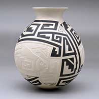 A black-on-beige jar with a recurved rim and decorated with a lightly-carved, sgraffito and painted two-panel fish and geometric design, click or tap to see a larger version