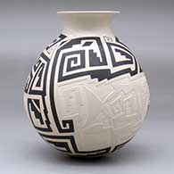A black-on-beige jar with a recurved rim and decorated with a lightly-carved, sgraffito and painted two-panel fish and geometric design, click or tap to see a larger version