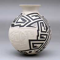 A black-on-beige jar with a recurved rim and decorated with a lightly-carved, sgraffito and painted two-panel fish and geometric design, click or tap to see a larger version