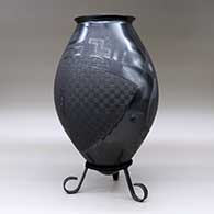 A matte and polished black jar with a flared rim and decorated with a sgraffito and painted two-panel serpent and geometric design, click or tap to see a larger version