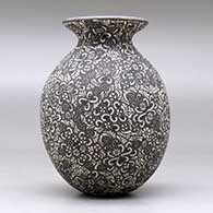 A black on white jar with a flared rim and decorated with a sgraffito geometric design, click or tap to see a larger version