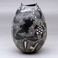 A black on white jar with a geometric cut opening and decorated with a sgraffito wildlife and geometric design, click or tap to see a larger version