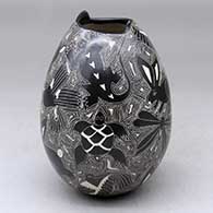 A black on white jar with a geometric cut opening and decorated with a sgraffito wildlife and geometric design
 by Alex Ortega of Mata Ortiz and Casas Grandes