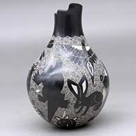 A black on white jar with a geometric cut opening on a short neck and decorated with a sgraffito wildlife and geometric design, click or tap to see a larger version