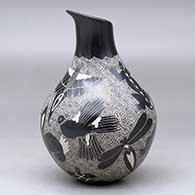 A black on white jar with a geometric cut opening on a short neck and decorated with a sgraffito wildlife and geometric design, click or tap to see a larger version
